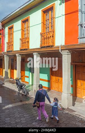Indigenous woman with child walking to school in front of colonial style architecture, Quito, Ecuador. Stock Photo