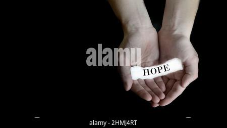 Person hands holding cupping paper message for hope on black background Stock Photo