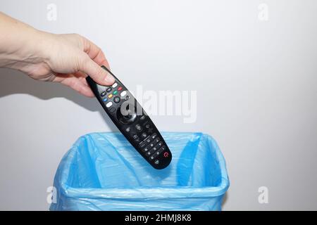 a woman's hand throws the TV remote control into the trash can close-up, copy space Stock Photo