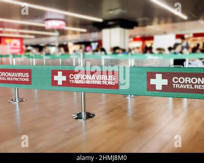 Green ribbon barrier inside an airport with the warning of travel restrictions due to the worlwide spread of Coronavirus Stock Photo