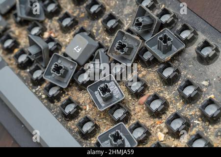 Close-up of a very dirty disassembled computer keyboard on the table. Disassembling a computer keyboard with your own hands, cleaning the keyboard Stock Photo