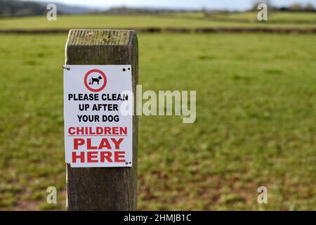 A sign fixed to a post asking dog owners and dog walkers to clear up any mess or fouling their dogs may make in an area where children play. Stock Photo