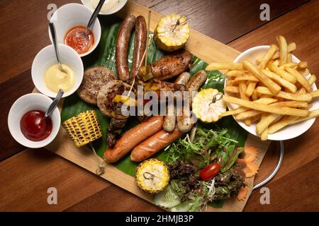 BBQ mixed meat platter with meatballs, sausages, skewers and chicken wings on wood background Stock Photo