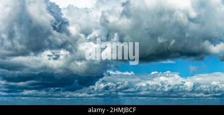 High resolution Panoramic background with blue day time sky and white and black clouds. Dramatic sky overly. Soft focus. Stock Photo