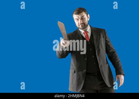 Threat to life. Dangerous man. The maniac is trying to kill a man. A bearded man in a suit with a red tie with a long knife in his hands. The killer s Stock Photo