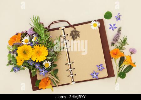 Old leather notebook with open blank pages for garden planner or botanical nature study with herbs and flowers used in natural plant remedies. Stock Photo