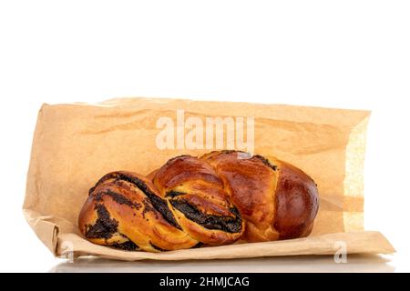 One flavorful homemade poppy seed bun with a paper bag, macro, isolated on a white background. Stock Photo