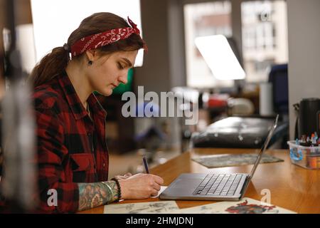 Young stylish lady tattoo master working in salon Stock Photo