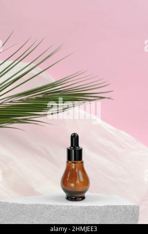 Natural essential oil or serum in a bottle with a pipette on a gray podium. Natural hyaluronic serum in bottles with a pipette Stock Photo