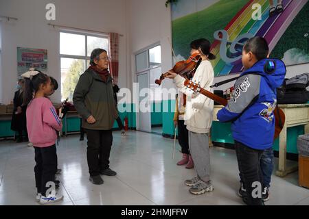 Beijing, China. 10th Feb, 2022. Undated photo shows Deng Xiaolan (2nd L) teaching kids music in Malan Village, Fuping County, north China's Hebei Province. Credit: Xinhua/Alamy Live News Stock Photo