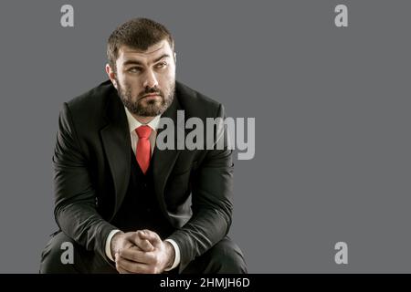 Brutal handsome man with a beard in a suit and red tie for a business meeting. Serious look. Boss. Boss. Businessman. Confident Stock Photo