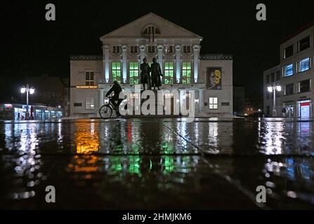 Weimar, Germany. 10th Feb, 2022. The neoclassical foyer on the second floor of the German National Theater in Weimar is illuminated in green behind the Goethe and Schiller monument on Theaterplatz. On the 'Day of Children's Hospice Work' on February 10, there are campaigns all over Germany to draw attention to the work of children's hospices and to raise funds. The German National Theater in Weimar is also taking part in the campaign and will be symbolically lit up in green during the evening hours. Credit: Martin Schutt/dpa-Zentralbild/dpa/Alamy Live News Stock Photo