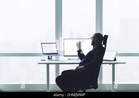 Faceless thoughtful businessman working on computer in equipped office Stock Photo