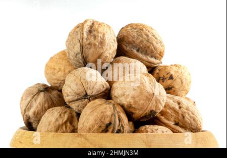Whole solid walnuts in wooden bowl on white background Stock Photo