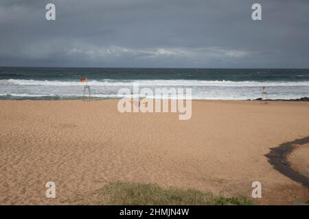 Golden sandy beach at Ballito, Kwa Zulu Natal, South Africa lapped by the warm waters of the Indian Ocean with warning signs for bathers and swimmers Stock Photo