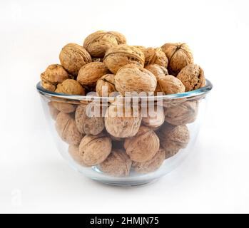 Whole solid walnuts in a glass bowl on white background Stock Photo