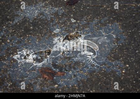 A cracked icy puddle and slippery surface on an asphalt road on a cold early morning in Huddersfield, West Yorkshire, U.K. Stock Photo