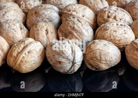 Whole solid walnuts on black reflective background Stock Photo