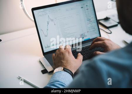 Anonymous male manager using netbook while analyzing financial charts in workplace Stock Photo