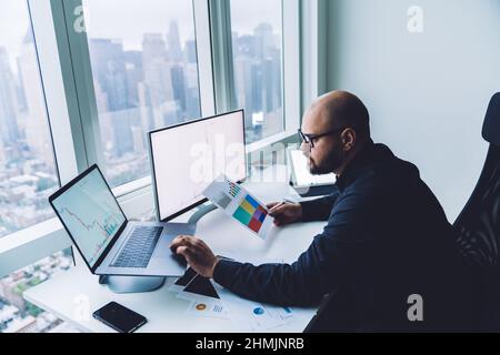 Focused male analyst working on laptop in modern workspace Stock Photo