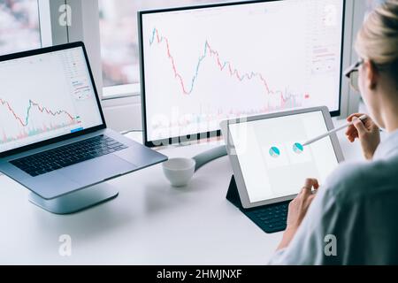Crop female broker analyzing charts on tablet in office Stock Photo