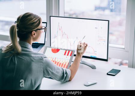 Unrecognizable trader analyzing graph on computer screen in office Stock Photo