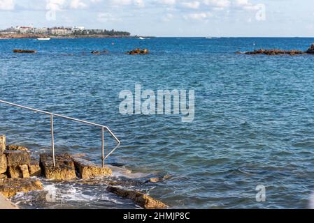 Descent into the sea from stone steps. Turquoise sea at the waterfront of the city of Paphos in Cyprus in autumn. Stock Photo
