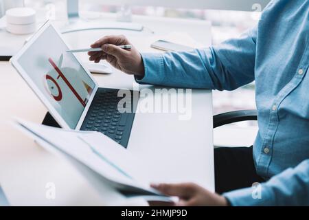 Crop man using stylus while working on tablet and analyzing documents Stock Photo