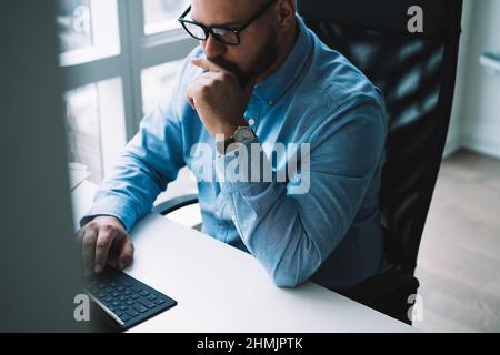 Focused young man working on netbook in light stylish office Stock Photo