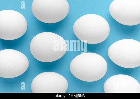 White chicken eggs on blue background.Close up Stock Photo