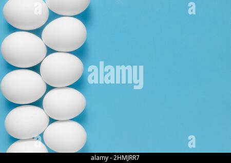 White chicken eggs on blue background.Close up Stock Photo