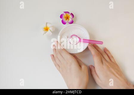 bowl with white clay powder. womans hands on white. Ingredients for facial and body mask or scrub Stock Photo
