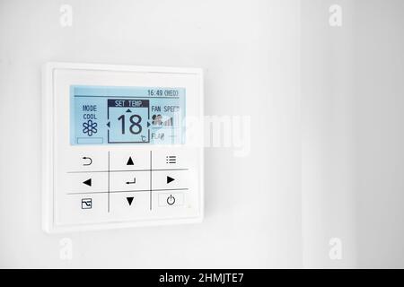Mounted on wall, climate control show 18 degrees indoor, remote air-conditioner inside smart home close up view, no people. Modern tech, comfort livin Stock Photo