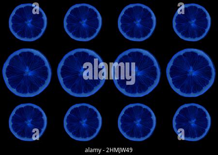 Seamless pattern of round blue slices of ripe lemon on a black background. Flat position, top view. High quality photo Stock Photo