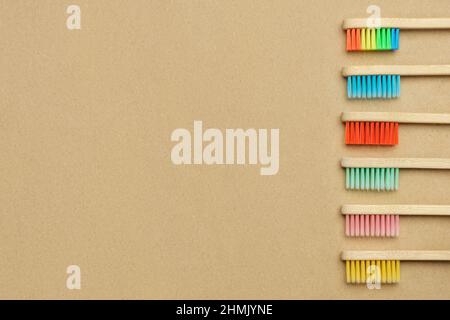 Multiple multicolor bamboo toothbrushes are lying on craft eco paper. Copy space, top view. Stock Photo