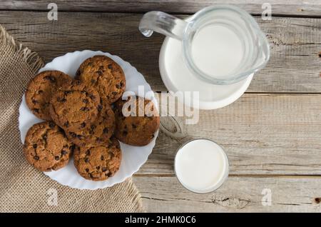 Biscuits, a jug and a glass of milk on burlap on old wooden table.The view from the top. Stock Photo
