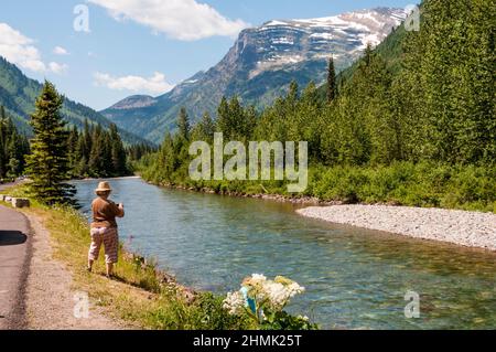 A tourist taking photographs at McDonald Creek, beside the Going-to-the-Sun Road in Glacier National Park, Montana, USA. Stock Photo