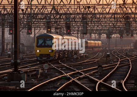 Northern Rail class 323 train glinting in the rising sun crossing a railway junction in the Manchester Picadilly station throat Stock Photo