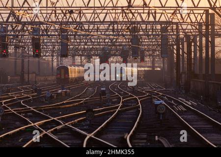 Trains arriving and departing in the Manchester Piccadilly station throat at sunrise in mid winter with red signals and complex trackwork Stock Photo