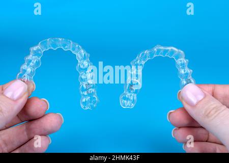 Transparent invisible brackets invisalign braces. Female caucasian hands holding two plastic aligners or retainers Stock Photo