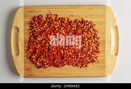 Dried red pepper powder. Background of crushed dry chili peppers on a wooden board. Top view. Stock Photo