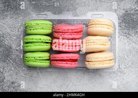 Sweet colorful macarons set, in plastic pack, on gray stone table background, top view flat lay Stock Photo