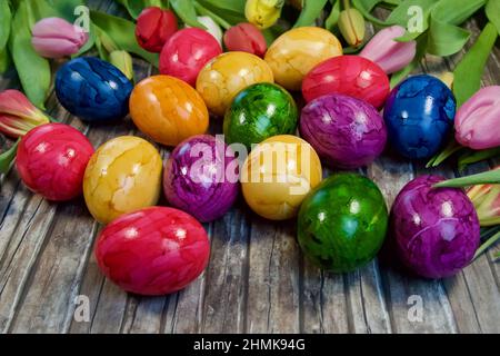 Closeup shot of painted Easter eggs with colorful tulips on a wooden surface Stock Photo