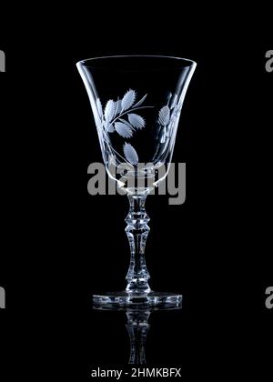 Empty crystal glass on black reflective surface with rim light Stock Photo