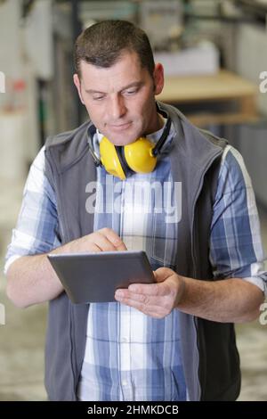 middle aged male worker using tablet in a factory Stock Photo