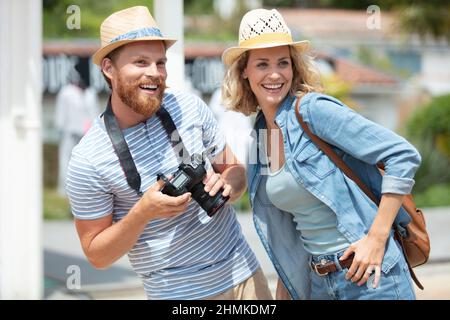young students couple tourists walking in city street taking photos Stock Photo