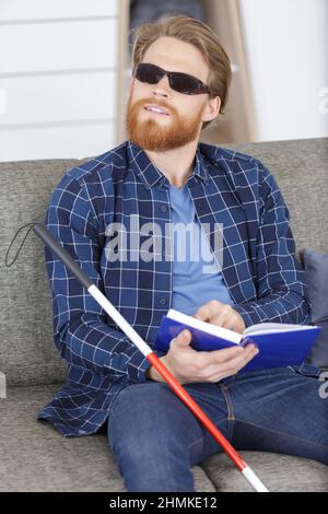 blind man reading braille book on the couch Stock Photo