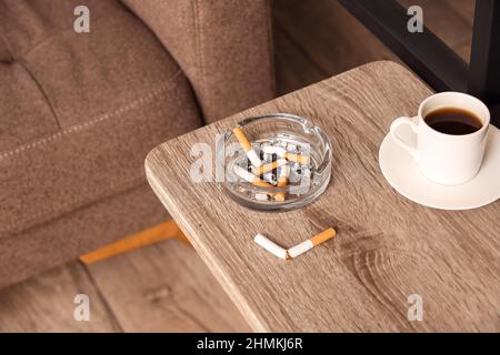 Ash tray with cigarettes and cup of coffee on table Stock Photo