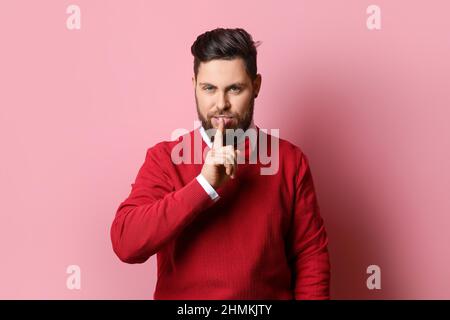 Stylish bearded man showing silence gesture on pink background Stock Photo