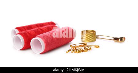 Red thread spools, safety pins and thimble on white background Stock Photo